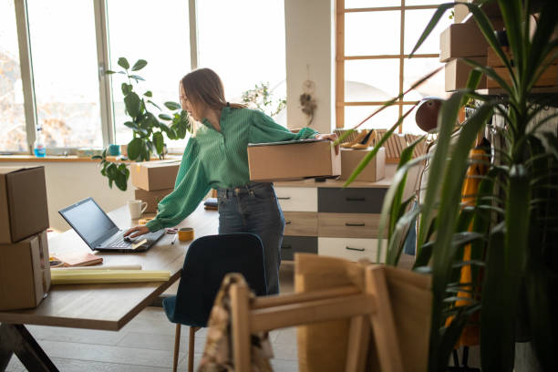 Person managing online fashion store amid parcels in home office, highlighting e-commerce's role in modern fashion.